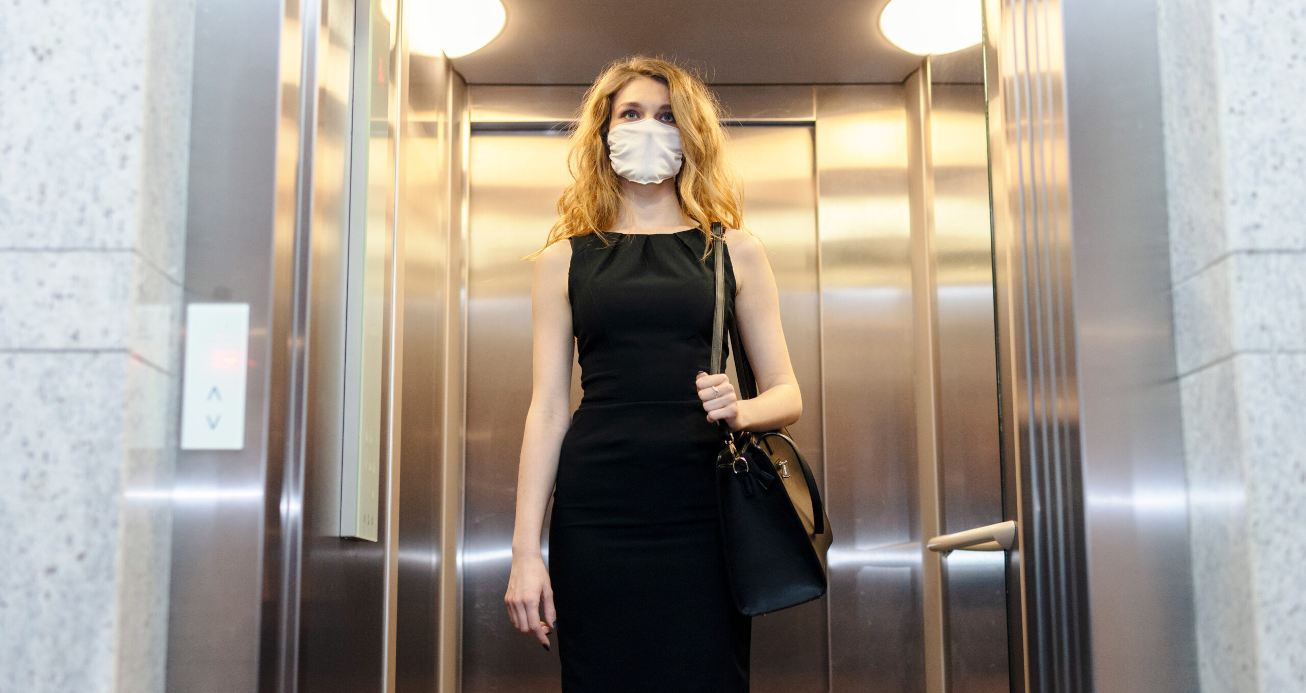 Vrouw in lift met mondkapje